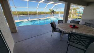 eine Terrasse mit Tisch und Swimmingpool in der Unterkunft SW Florida Waterfront Home in Cape Coral