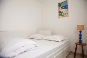 ポルニシェにあるAu coeur de ville - à proximité de toutの白いベッド(白い枕2つ、ランプ付)