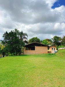 a brick building in a grassy field with a house at Sítio Pand'Oro in Atibaia