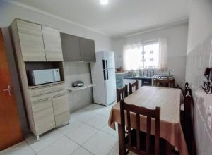 a kitchen with a table and a white refrigerator at Básico & Aconchegante in Itajubá