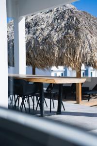a wooden table with chairs and a straw umbrella at 'Casa 30' Villa nearby Mambo-Beach in Willemstad