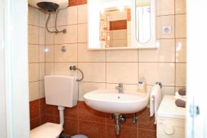 een badkamer met een wastafel, een toilet en een spiegel bij Apartment Ana Banana in Zadar