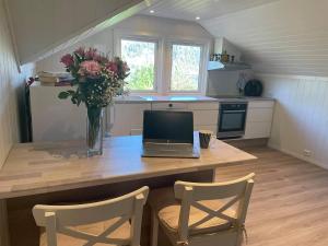 a kitchen with a table with a laptop and flowers at Apartment with sea view in Stathelle