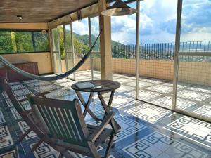a porch with a hammock and a chair and a table at Cozy House in Rio de Janeiro