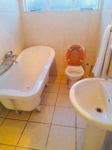 a bathroom with a tub and a toilet and a sink at Signature Guesthouse in Ventersburg +16 photos