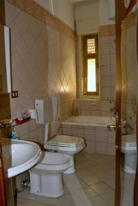 ein Badezimmer mit 2 WCs, einem Waschbecken und einer Badewanne in der Unterkunft La luna nel Cortile in Serradifalco