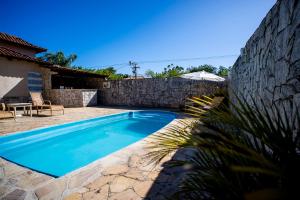 a swimming pool in front of a stone wall at Pousada Maria Maria Búzios in Búzios