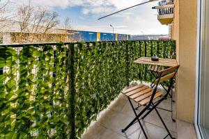 a balcony with a green privacy fence and a table at Charming Apartment - Swimming Center, Airport & Therme SPA in Otopeni