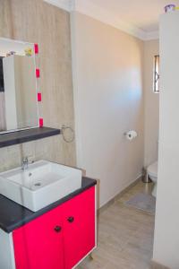 a bathroom with a white sink and a red cabinet at Modern and Executive 2 Bedroom Townhouse in Bloemfontein +18 photos