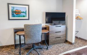 a room with a desk and a tv and a table and chairs at My Place Hotel-East Moline/Quad Cities, IL in East Moline