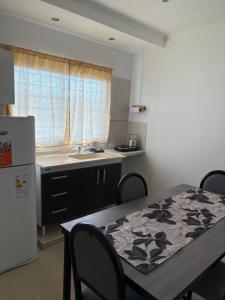 a kitchen with a table and a sink and a refrigerator at DEL SOL APARt TERMAL V in Termas de Río Hondo