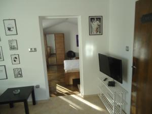 a living room with a television on a white wall at Apartman Sweet Home in Palit