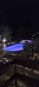a swimming pool lit up in the dark at night at Levendulás Ház Balatonakarattya in Balatonkenese