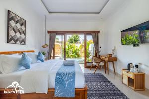 a bedroom with a bed and a desk and a window at Rashita Homestay by Bukit Vista in Uluwatu