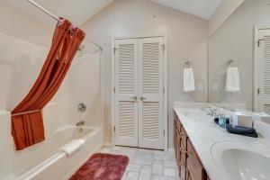 Un baño blanco con bañera y lavabo. en Walk to Branson Strip Inviting Condo!, en Branson 18 fotos más