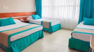 ein Hotelzimmer mit zwei Betten und blauen Vorhängen in der Unterkunft Hotel Portobelo beach in San Andrés