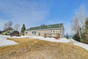una casa blanca con techo verde en la nieve en Lakefront Home with Yard and Views in Cheboygan!, en High Banks