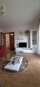 a living room with a glass table and a television at Buarcos Beach House in Buarcos