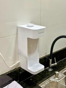 a white soap dispenser on a counter next to a sink at Apartamento Palmeira Espaço Conforto e Conectividade em Formosa in Formosa