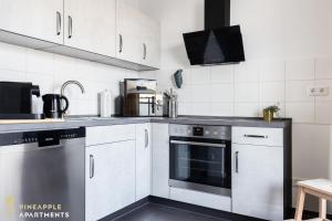 eine Küche mit Küchengeräten aus Edelstahl und weißen Schränken in der Unterkunft PINEAPPLE APARTMENTS - Zwinger XI - 64qm in Dresden