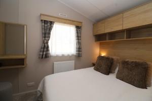 a bedroom with a white bed and a window at The Roost - Family Friendly caravan near Glastonbury & Street in Compton