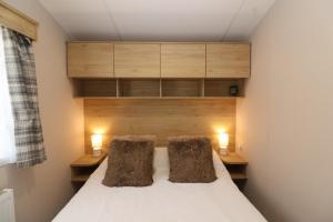 a bedroom with a bed with two pillows at The Roost - Family Friendly caravan near Glastonbury & Street in Compton +9 photos