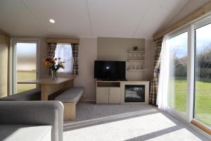 a living room with a couch and a tv and a fireplace at The Roost - Family Friendly caravan near Glastonbury & Street in Compton