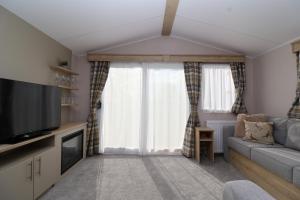 a living room with a couch and a tv at The Roost - Family Friendly caravan near Glastonbury & Street in Compton