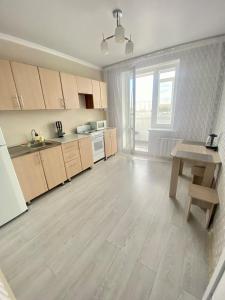 a kitchen with wooden cabinets and a table in it at Уютные апартаменты в новом жилом комплексе in Kostanay