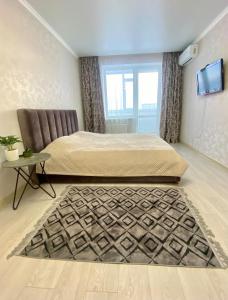 a bedroom with a bed and a table and a television at Уютные апартаменты в новом жилом комплексе in Kostanay