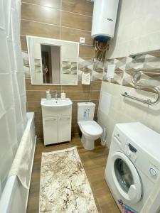 a bathroom with a toilet sink and a washing machine at Уютные апартаменты в новом жилом комплексе in Kostanay +5 photos