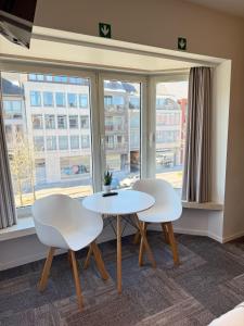 two white chairs and a table in front of a window at Vernieuwde kamers in het centrum van Brugge in Bruges