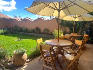 two tables and chairs with an umbrella on a patio at Hotel Chinchero Boutique & Tours in Chinchero