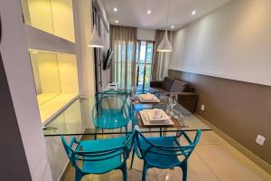 a dining room with a glass table and blue chairs at Premium Flat Ponta Negra Natal in Natal