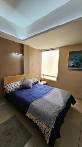 a bedroom with a bed with a blue comforter and a window at A10 SUITE WHITE para 1 a 2 personas, Especialistas en CORTAS, MEDIANAS Y LARGAS ESTANCIAS en IZCALLI TEPOTZOTLAN perfecto para Familias, Turistas, Contratistas, Estudiantes, Empresas A sólo 5 min Izcalli 5 min Esmeralda 20 min Satélite 25 min AIFA in Cuautitlán Izcalli