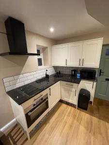a kitchen with white cabinets and black counter tops at Low Fellside in Kendal +11 photos
