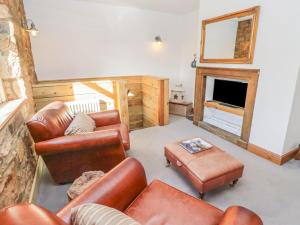 a living room with leather furniture and a fireplace at Seafield Granary in Alnwick