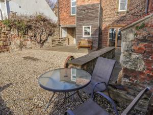 a glass table and chairs on a patio at Seafield Granary in Alnwick