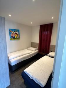a bedroom with two beds and a painting on the wall at Marina Strandbad Chalet RiverLodge mit Zaun Haus Nr 94 in Olburgen