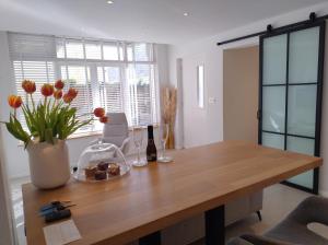 ein Holztisch mit einer Vase mit Blumen darauf in der Unterkunft Beach House Rodine - free parking & bikes in Scheveningen