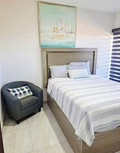 a bedroom with a bed and a chair and a painting at Marina Cerritos Azul Turquesa #3 - 4 Albercas - 1 Min Playas in Mazatlán