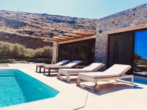 a group of lounge chairs next to a swimming pool at Kythnian Retreat in Kithnos