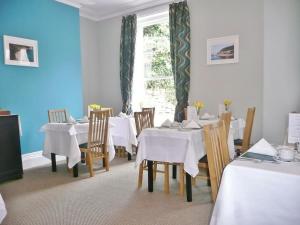 a dining room with white tables and chairs and a window at The Bahamas in Torquay