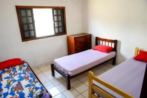 a small room with two beds and a window at Casa com otima localizacao e churrasqueira in Ilhabela