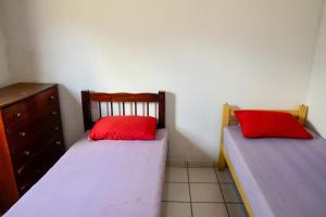 two beds with red pillows in a bedroom at Casa com otima localizacao e churrasqueira in Ilhabela