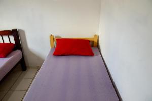 a bed in a room with a red pillow on it at Casa com otima localizacao e churrasqueira in Ilhabela