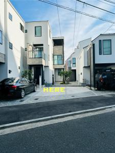 a car parked in a parking lot next to some buildings at A newly built house a 4 minute walk from the station, Free parking & Let's enjoy the night view together! in Tokyo