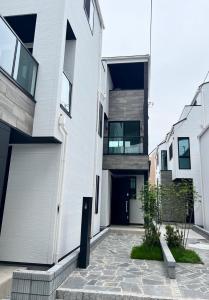 a white house with a black door and a courtyard at A newly built house a 4 minute walk from the station, Free parking & Let's enjoy the night view together! in Tokyo