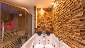 a bath tub in a bathroom with a wooden wall at Wood 47 spa in Précy-sur-Oise