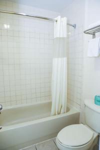 a bathroom with a toilet and a bath tub with a shower curtain at Starlite Motel in San Antonio
